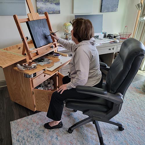 Woman in desk chair working on painting